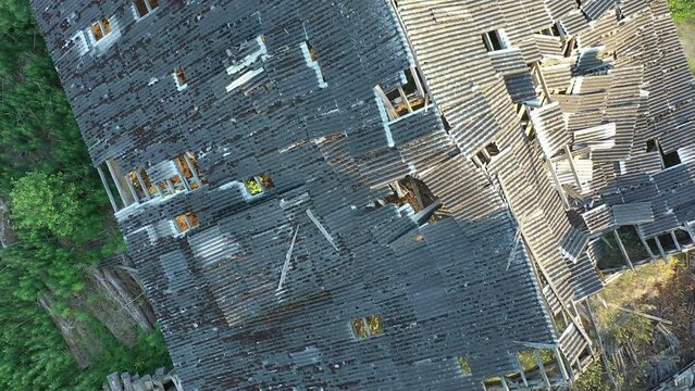 Koeru.Estonia-July 5.2021: Aerial shot of a ruined rooftop of a soviet cattle barn. Abandoned old structure slowly decaying. Drone slowly moving backwards with the camera pointed downwards.