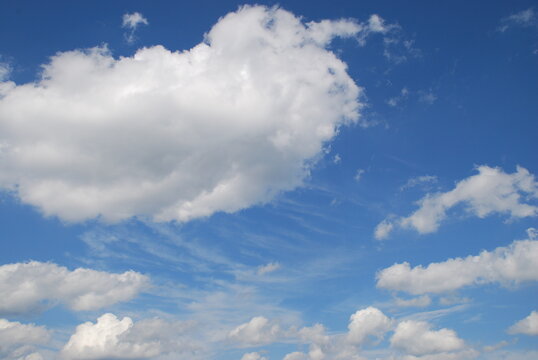 Overcast at different heights. Light blue sky, high cirrus clouds and low cumulus clouds float across the sky. Descent clouds are translucent, dense white cumulus clouds.