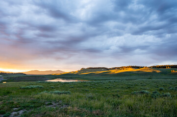 Obraz premium Thick Clouds Catch The Sunset Colors Over Hayden Valley and The Yellowstone River