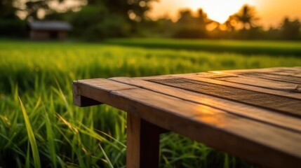 Fototapeta premium old wooden table next to green rice fields in the evening at sunset