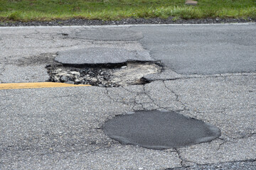 Damaged american road surface with deep pothole. Ruined street in urgent need of repair