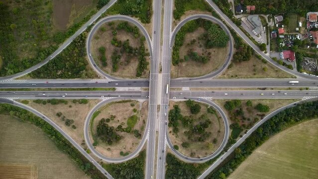 Aerial high angle footage of a highway cloverleaf intersection. East European traffic seen from a drone. Summer aerial shot of vehicles navigating massive intersection in Sofia Bulgaria.
