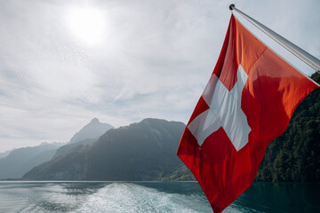 A Swiss flag at the stern of a passengers boat on the lake of Lucerne, Switzerland. - obrazy, fototapety, plakaty