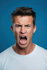 Portrait of caucasian man in white shirt who is screaming isolated over blue background.