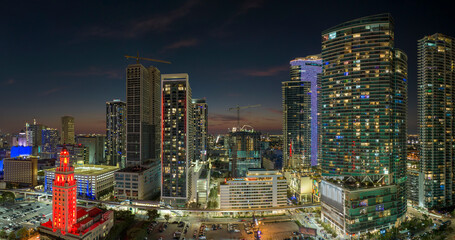View from above of brightly illuminated skyscraper buildings in downtown district of Miami Brickell in Florida, USA at night. American megapolis with business financial district