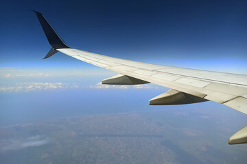 View through airplane window of commercial jet plane wing flying high in the sky. Air travelling concept