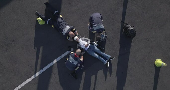 Emergency, injury and aerial of people on road for accident, first aid and car crash for saving patient. Paramedic, ambulance and health emt with person for medical service, care and healthcare