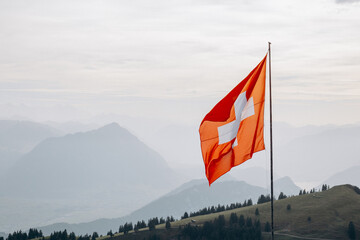 A large swiss flag evolves against the background of the swiss alps, the swiss flag on top of the...