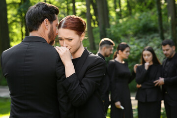 Sad people in black clothes mourning outdoors. Funeral ceremony