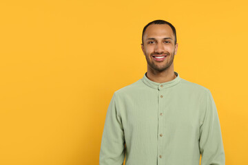 Portrait of handsome young man on orange background, space for text