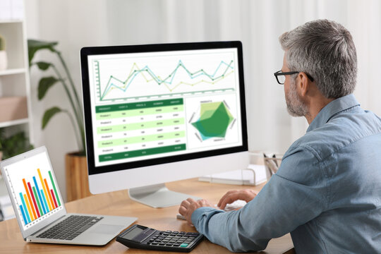 Professional accountant working at wooden desk in office, back view
