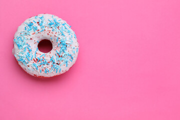 Sweet glazed donut decorated with sprinkles on pink background, top view and space for text. Tasty confectionery
