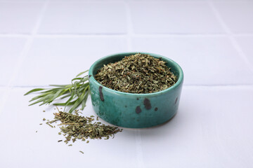 Dry and fresh tarragon on white tiled table