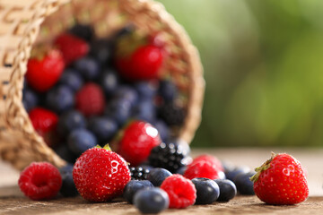 Different fresh ripe berries on wooden table outdoors, closeup