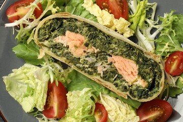Piece of tasty strudel with salmon, spinach and salad on plate, top view