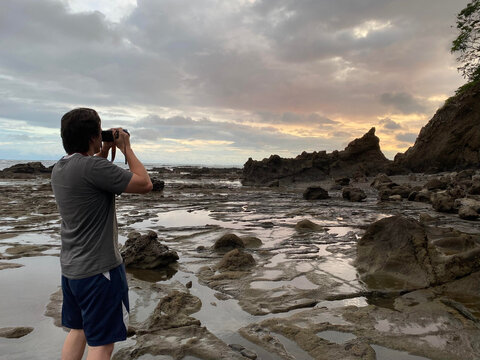 a man taking photos on the beach of costa rica 