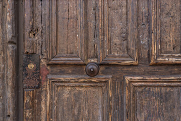 Fototapeta na wymiar Access portal to a period building with a wooden door with a rusty knob