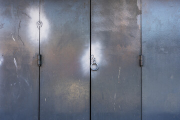 Some old folding garage doors with hinges and a ring handle