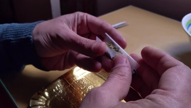 Hands of A Man Rolling a Joint at His Home. Close Up.