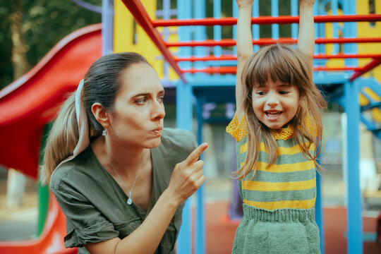 Mom Forbidding her Child to Climb on a Dangerous Playground Equipment. Caregiver babysitting applying strict safety rules for the little kid
