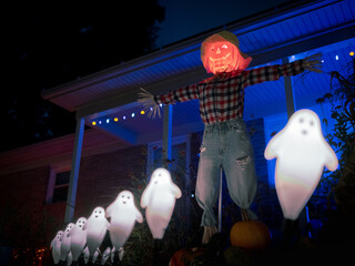 Scarecrow with pumpkin head in line of ghosts