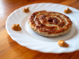 Traditional German Delicious Bratwurst Snail with Bavarian Mustard on a White Plate