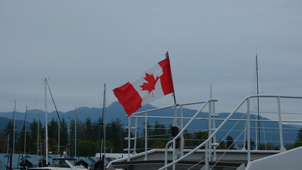 Fototapeta premium Flag of Canada on a yacht waving in the wind on a dark cloudy day