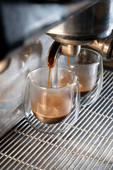 Coffee is poured into glass glasses in a coffee machine