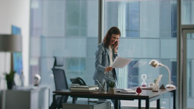 Calling woman rejoicing business success throwing papers standing workplace.