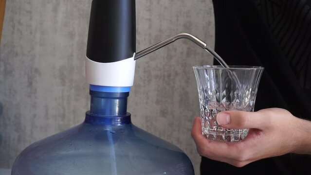 Filling water from the demijohn into a glass. Filling a glass with water to drink. Filling a glass of water.