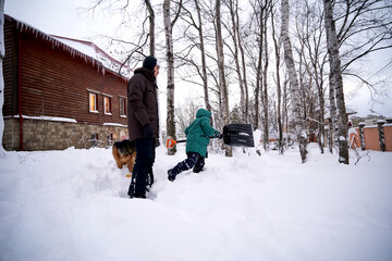 A family builds a slide in the yard in winter.