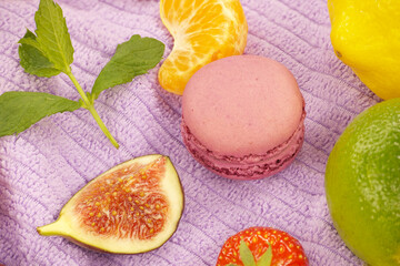 Group of colorful macaroons and fruits on purple towel