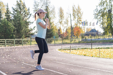 A young beautiful woman in sportswear plays sports at a local stadium. Exercise, jog and exercise at the beginning of the day. Healthy and active lifestyle.