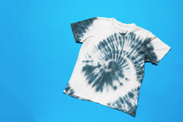 T-shirt with a dark tie dye pattern on a blue background. The concept of self-dyeing clothes.