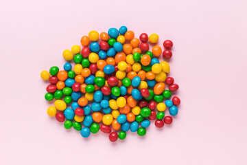 A bunch of colorful candies on a pink background.