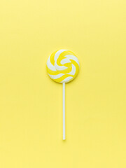 Round yellow lollipop on a yellow background. The concept of sweets.