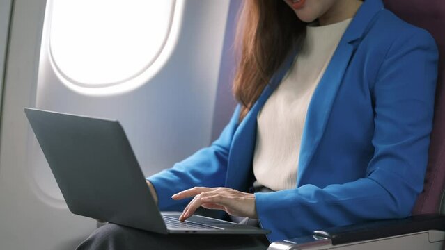 Asian young woman using laptop sitting near windows at first class on airplane during flight,Traveling and Business concept