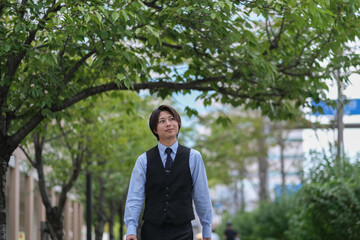 街路樹の道を歩くビジネスマン