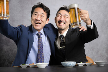 生ビールで乾杯するサラリーマンのカメラ目線　忘年会や新年会 イエ～～イ！！