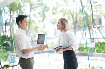 Businessman And Businesswoman Shaking Hands In Office congratulating with getting new job, manager making great deal with customer, diverse business partners