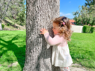 Cute little girl is playing around the grass and trees at the park
