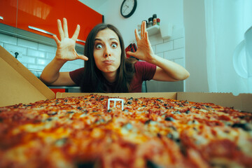 Woman Looking at the Huge Mind-Blowing Pizza She Ordered. Hungry girl eating a fast food for...
