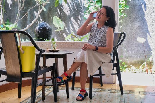 Woman sitting alone in her home terrace making a phone call