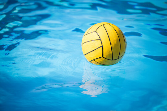 A yellow water polo ball floating in a swimming pool