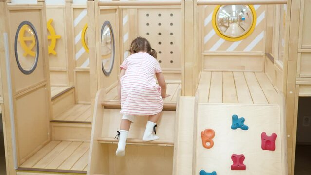 Active Little Girl Climbs Up and Moves Though  in Playroom Obstacle Course in Playroom