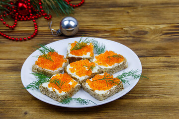 Canapes with red caviar and Christmas decorations on wooden table