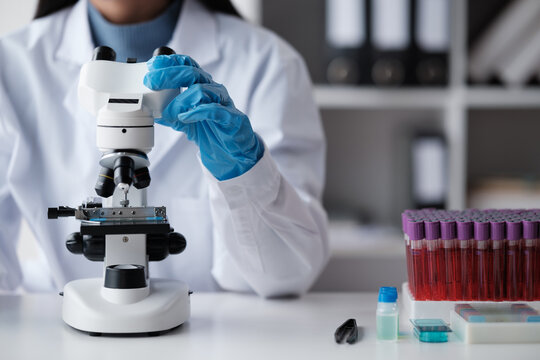 Scientist in a laboratory microscope with microscope slide in hand