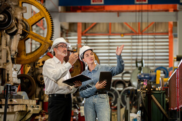 partner woman engineer assistant in helmet inspection check heavy machine construction installation in industrial metal roof roll sheet factory with colleague manager. partnership operation factory