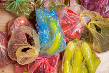bananas, zucchini, tomatoes and other vegetables and fruits in multi-colored plastic bags. flatlay