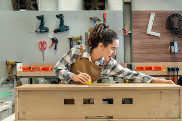 One Strong confident young aged women carpenter standing aim at wood plank in workshop. Latin female carpenter entrepreneur working craft with wood diy tool in workbench shop carpentry - obrazy, fototapety, plakaty